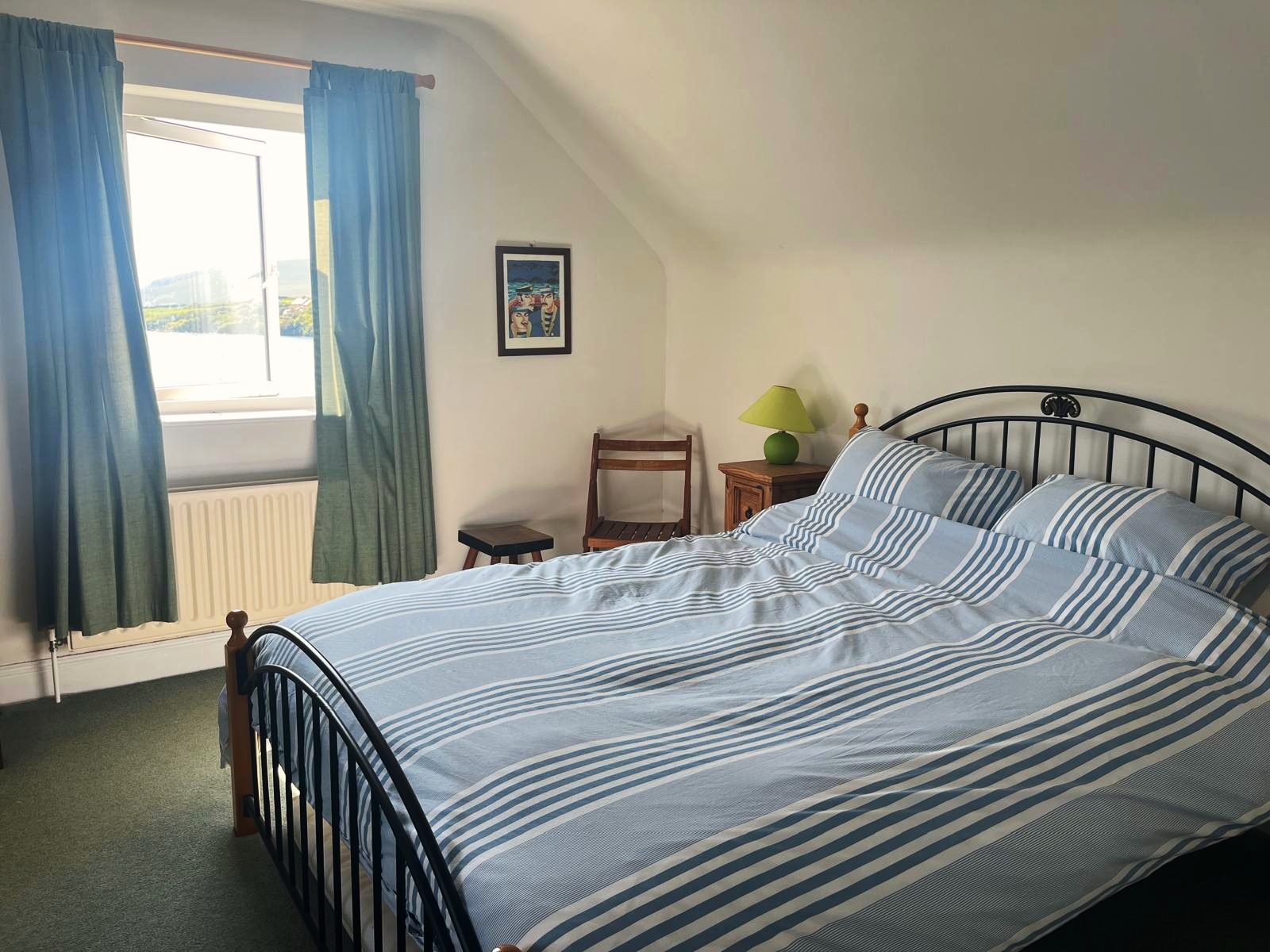Double bed with striped linen and a window onto the sea