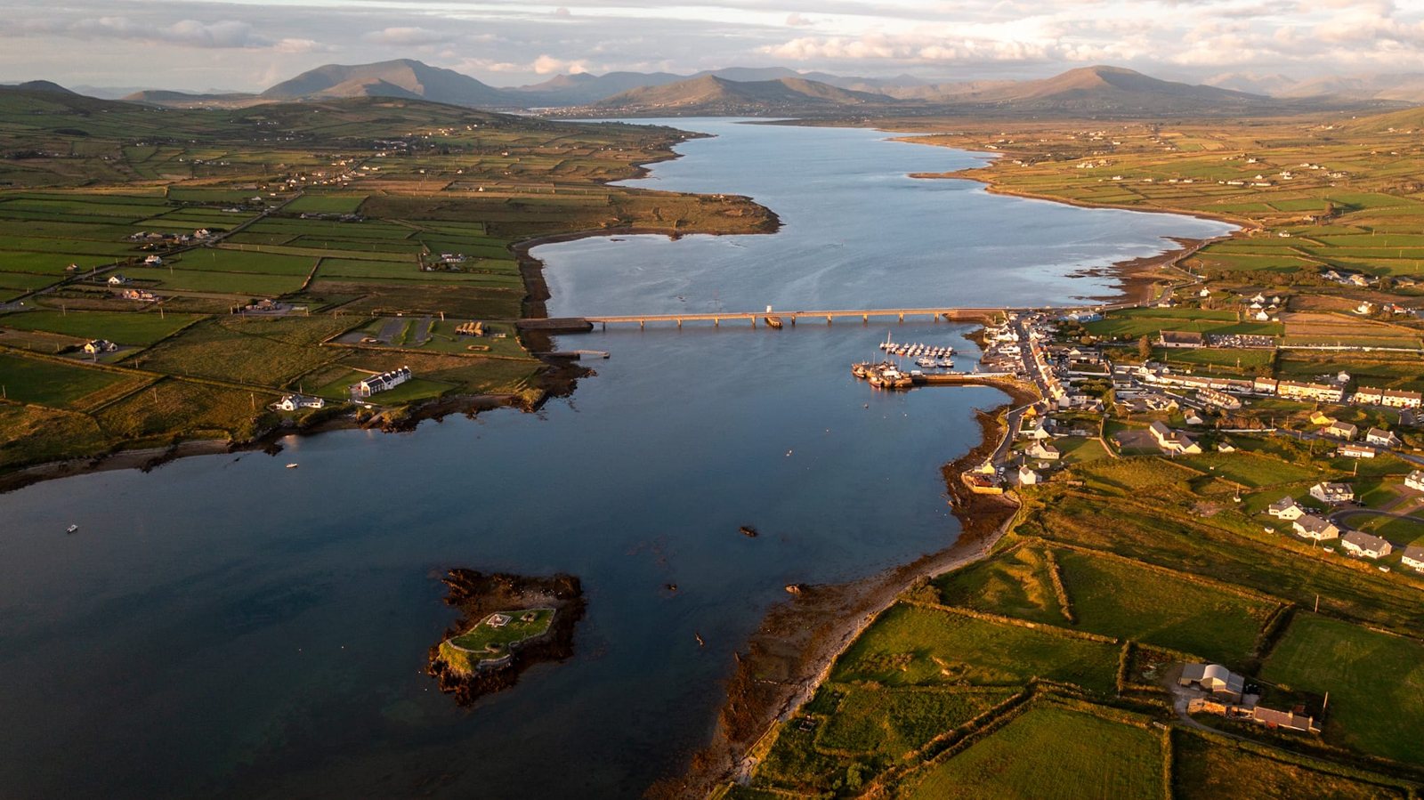 Aerial view at sunset of the bridge from Valentia to Portmagee, with the harbour and mountains beyond