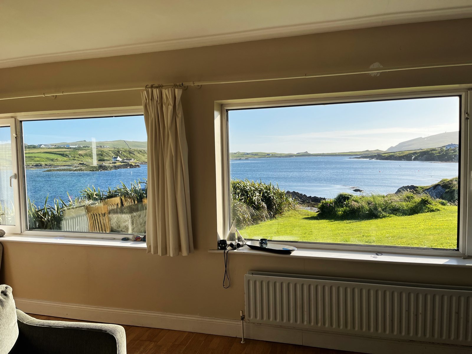 Two large living room windows looking out over the lawn and the harbour